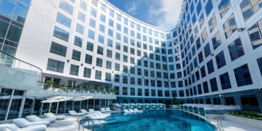 The pool at the hotel is bordered by white lounge chairs, inviting guests to relax and enjoy the surroundings.